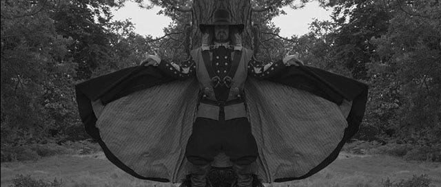 Black and white shot of a 16th century civil war soldier with a wide braimmed hat, raising his cape. There is a mirror effect at the center of the photo making each side of the iage a reflection of the other.