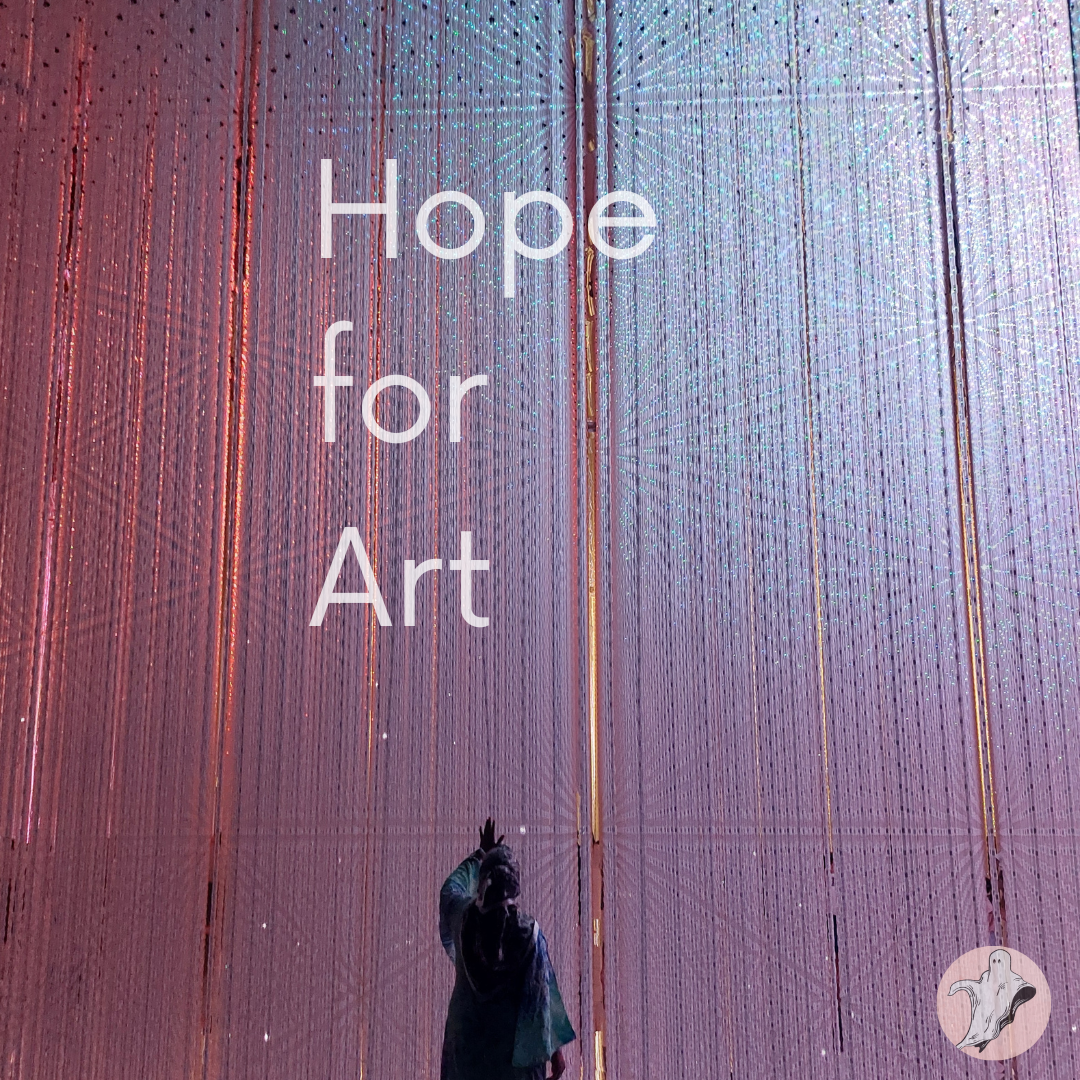 A large curtain of glass and light stands in front of a woman with her back to the camera while she reaches up to touch it. The Text above her reads - Hope for Art.